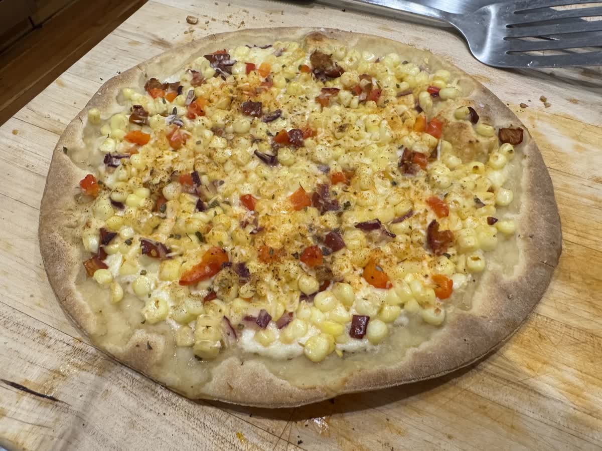 pizza topped with corn, peppers, onions, and cheese
